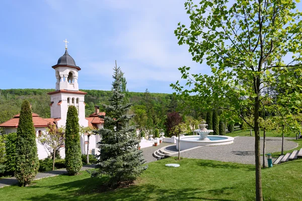 Campanario y cuenca en el monasterio ortodoxo de Curchi en Moldavia con árboles verdes y cielo azul — Foto de Stock