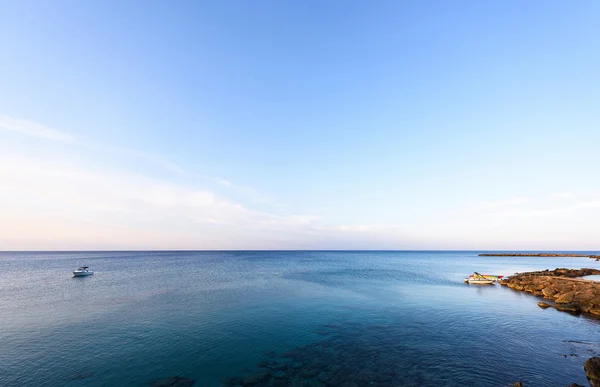 Foto av havet i protaras med stenar, Cypern ö med båtar i solnedgången. — Stockfoto