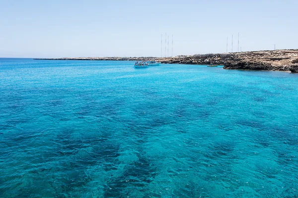 Blå lagunen med båtar och simning människor i protaras paralimni, obefläckade vatten, blått hav och klippor, Cypern ö — Stockfoto