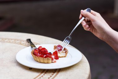 Bir restoran masada beyaz tabakta çilek, nane ve blackcurrant, meyveli pasta kesme eller fotoğraf.