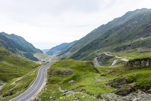 Foto de la famosa carretera sinuosa en las montañas Fagaras al atardecer, Rumania . — Foto de Stock