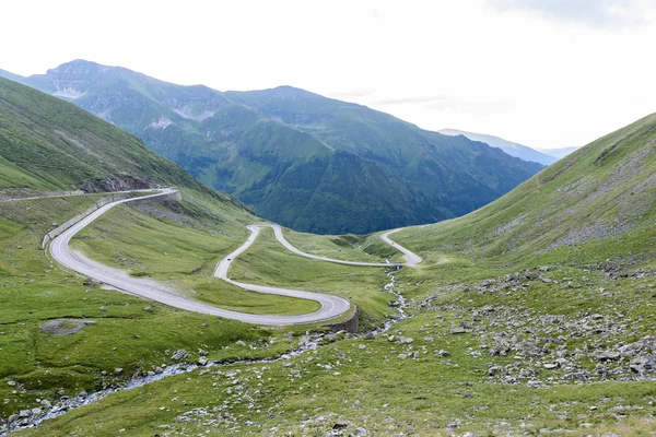 Foto da famosa estrada sinuosa em fagaras montanhas ao pôr do sol, Roménia . — Fotografia de Stock