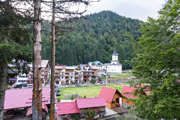 Photo de sommets verts et d'un village touristique avec église bleue dans les montagnes de fagaras, Roumanie . — Photo
