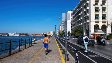 THESSALONIKI, GREECE - 21 Eylül 2020: Geçen arabaları, yüksek binaları ve deniz kıyıları olan yürüyen insanlar
