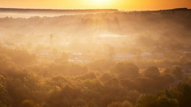 Moldova 'da güneş doğarken sislerin arasından görülebilen yerleşim evleri ve çoklu yeşilliğe sahip bir köy