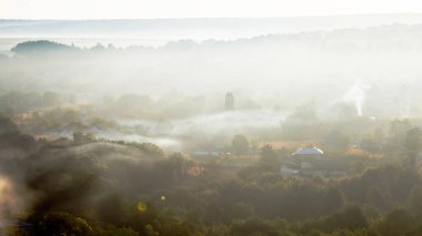 Moldova 'da güneş doğarken sislerin arasından görülebilen yerleşim evleri ve çoklu yeşilliğe sahip bir köy