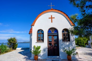 Nea Roda köyünün tepelerinde turuncu ve beyaz kilise ve Yunanistan 'ın Halkidiki kentindeki liman