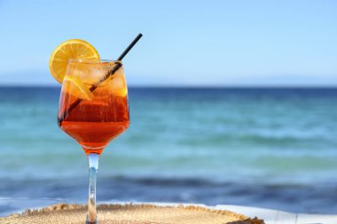 Kırmızı kokteyl, turuncu dilimli ve deniz zemininde buz.