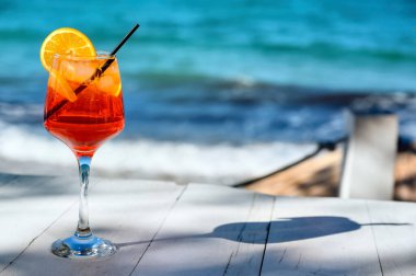 Kırmızı kokteyl, turuncu dilimli ve deniz zemininde buz.