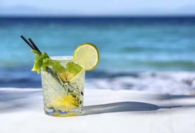 Limon dilimli beyaz mojito kokteyli ve deniz zemininde buz.