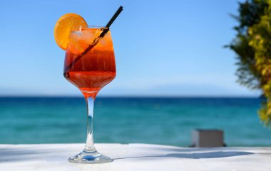 Kırmızı kokteyl, turuncu dilimli ve deniz zemininde buz.