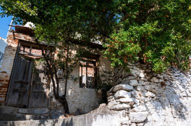 Kırık camları ve kapısı olan, dış görünüşü kötü olan, Yunanistan 'ın Kavala kentinde ağaçların büyüdüğü eski ve terk edilmiş bir ev.