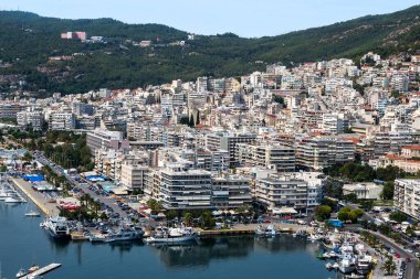 Birden fazla konut ve devlet binası, arka planda yeşil tepeler, Yunanistan 'ın Kavala kentinde demirli yatları olan Ege deniz maliyeti