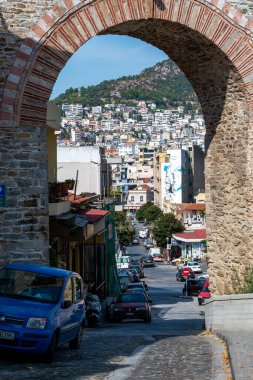 KAVALA, GREECE - 23 EYLÜL 2020: Otomobilleri park edilmiş dar sokaklar ve su kemerinin kemerinden geçen tepedeki birçok binanın manzarası