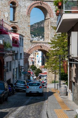 KAVALA, GREECE - 23 Eylül 2020: Arabaları ve binaları olan dar bir sokak, ön planda su kemeri