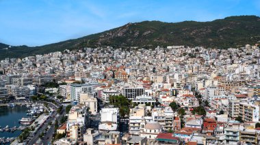 KAVALA, GREECE - 23 Eylül 2020: Birden fazla konut ve devlet binaları, arka planda yeşil tepeler, demirli yatlarla Ege denizi maliyeti