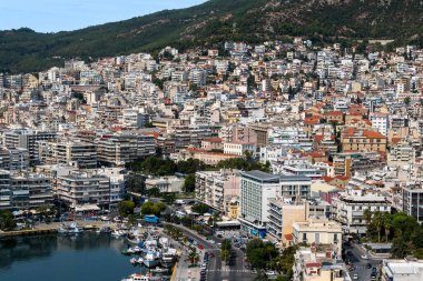 KAVALA, GREECE - 23 Eylül 2020: Birden fazla konut ve devlet binaları, arka planda yeşil tepeler, demirli yatlarla Ege denizi maliyeti