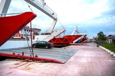 Demir atmış, dış yüzeyleri kırmızı feribotlar, Thassos limanında iskeleler açılmış, bir araba Yunanistan 'da gemiden ayrılıyor.