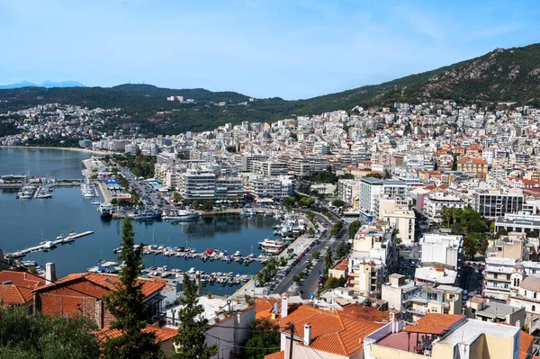 Birden fazla konut ve devlet binası, arka planda yeşil tepeler, Yunanistan 'ın Kavala kentinde demirli yatları olan Ege deniz maliyeti