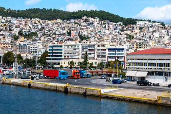 Ege Denizi 'ndeki çok sayıda bina liman, demirli yatlar ve otoparkta park etmiş kamyonlar, Yunanistan' ın Kavala kentindeki yeşil tepe