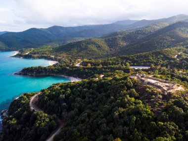 Yunanistan 'ın Ege deniz maliyeti, kıvrımlı yollar, yemyeşil tepeler, antik kalıntılar, insansız hava aracı manzarası, Yunanistan