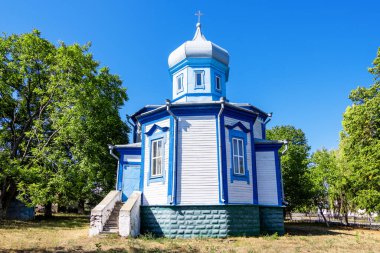 Horodiste Kilisesi beyaz ve mavi cepheli, yeşil ağaçlarla çevrili, ahşap ve metalden yapılmıştır, Moldova