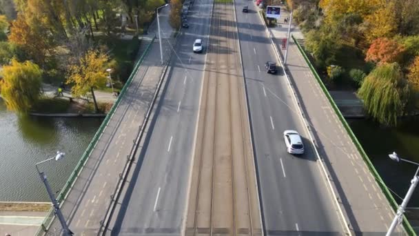 BUCHAREST, RUMANIA - 18 DE OCTUBRE DE 2020: Una carretera sobre el agua con coches en movimiento y personas caminando en el parque Titan, múltiples zonas verdes y edificios residenciales. Vista desde el dron — Vídeo de stock