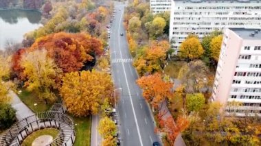 Göl kenarındaki Titan parkı ve çok renkli ağaçlar, hareket halindeki arabalarla yol ve parkın yakınındaki konut binaları. İHA, Bükreş ve Romanya 'dan görüntü