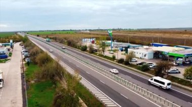 ROMANIA, 18 Kasım 2020: yol kenarlarında hareket halindeki otomobiller ve benzin istasyonları olan otoyol. İnsansız hava aracından görüntüle