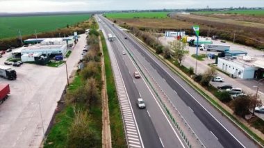 ROMANIA, 18 Kasım 2020: yol kenarlarında hareket halindeki otomobiller ve benzin istasyonları olan otoyol. İnsansız hava aracından görüntüle