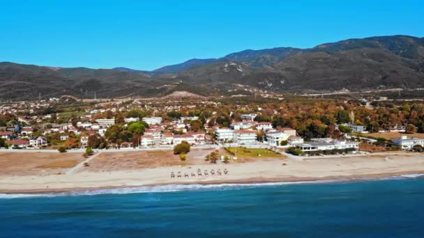 Panorama da Asprovalta com edifícios e vegetação, colinas verdes. Longa praia com guarda-sóis e espreguiçadeiras. Dia ensolarado. Grécia — Vídeo de Stock