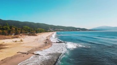 Ege kıyılarının hava manzarası, dalgalı ve köpüklü uzun sahil, solda yeşillik.