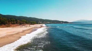 Ege kıyılarının hava manzarası, dalgalı ve köpüklü uzun sahil, solda yeşillik.