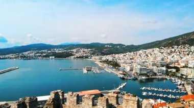 Kavala 'nın havadan görünüşü, bir sürü bina, Ege kıyıları, uzaktaki yeşil tepeler. İnsansız hava aracı antik kale duvarının arkasından uçuyor. Yunanistan