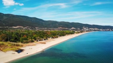 Yeşillik ve arka planda yeşil tepeler olan Ege deniz kıyısının panoraması. Long Beach. Güneşli bir gün. Asprovalta, Yunanistan