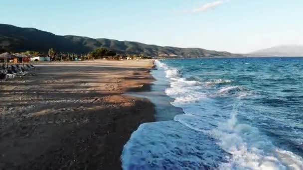 View of Aegean sea coast in Asprovalta at sunset from the drone. Sunbeds with umbrellas. Rough sea, waves with foam. Greece — Stock Video