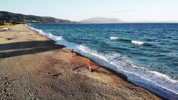 Вид на узбережжя Егейського моря в Азпровальті на заході сонця з дрона. Рибалки на пляжі за угодою. Важке море, хвилі з піною. Греція — стокове відео