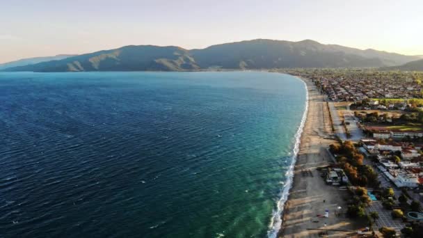 Vista da costa do mar Egeu em Asprovalta ao pôr do sol a partir do drone. Múltiplos edifícios e vegetação. Mar agreste, ondas com espuma. Grécia — Vídeo de Stock