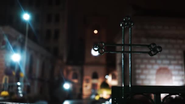 A metal green cross at night with buildings on the background in Bucharest, Romania — Stock Video