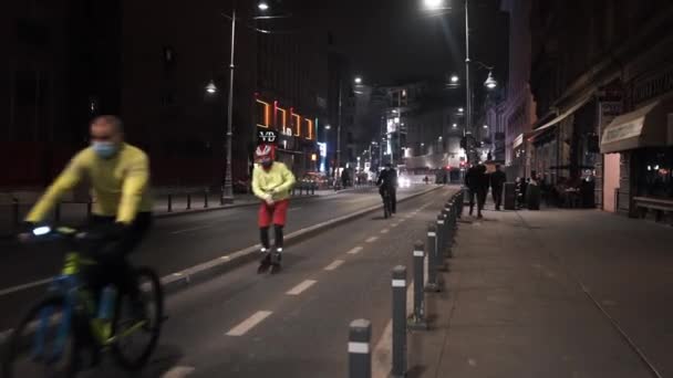 BUCHAREST, ROMÁNIA - NOVEMBER 21, 2020: Street scape at night with bike path on a road, moving cars, waking people and riding cyclists, illumination — Stock videók