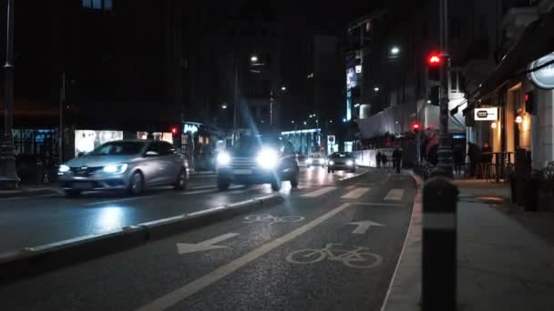 BUCHAREST, ROMANIA - NOVEMBER 21, 2020: Street scape at night with bike path on a road, moving cars, waking people and riding cyclists, illumination — Stock Video