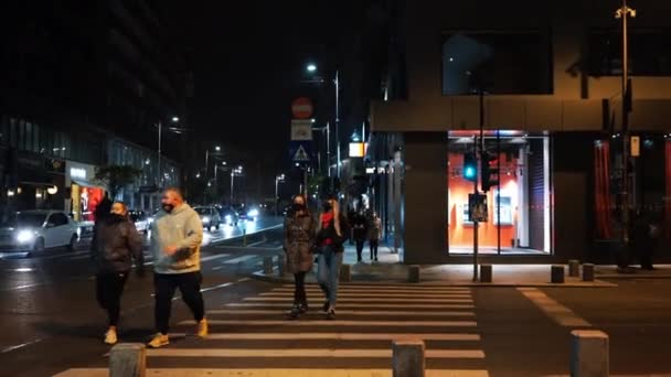 BUCHAREST, ROMÁNIA - NOVEMBER 21, 2020: Utcai táj éjjel egy út mozgó autókkal és emberekkel az úton, megvilágítás — Stock videók