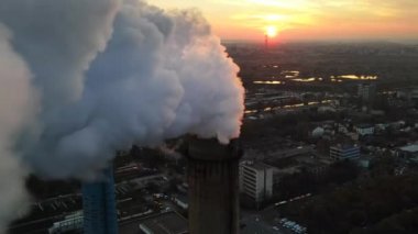 Gün batımında Bükreş 'te bir sürü tüp ve tesisi olan bir elektrik santrali. Tüpün içinden bir sürü köpük çıkıyor. Şehir manzarası, insansız hava aracı, Romanya