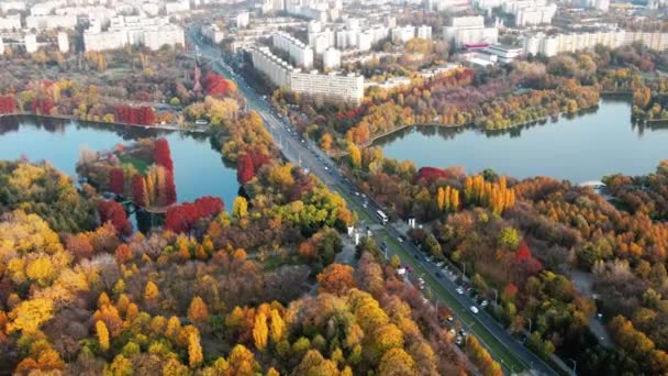 Une route avec des voitures en mouvement près du lac du parc Titan, de multiples espaces verts et des bâtiments résidentiels. Vue depuis le drone, vue panoramique, Bucarest, Roumanie — Video