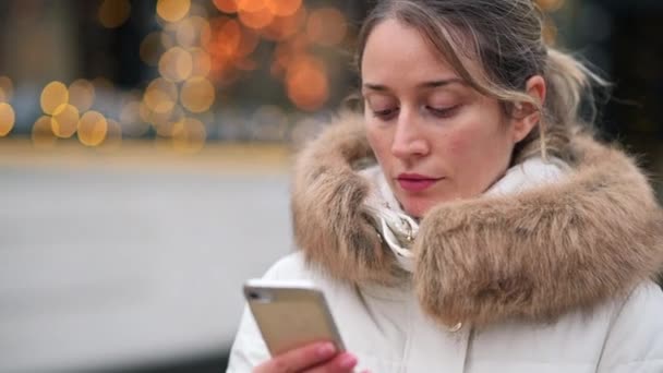 Kobieta Białym Płaszczu Zimowym Pracująca Telefonie Komórkowym Rynku Świątecznym Uśmiechniętymi — Wideo stockowe