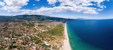 Asprovalta ve Ege 'nin panoraması, birden fazla bina, kasaba boyunca uzun sahil, arka planda yeşil tepeler, Yunanistan