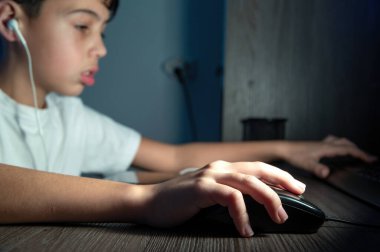 Oğlan geceleri kulaklıkla bilgisayar kullanıyor. Yorgun yüz