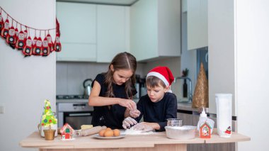 Kardeşler mutfakta yemek pişiriyor, Noel şapkalı çocuk. Mutlu çocuk fikri