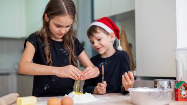 Kardeşler mutfakta yemek pişiriyor, Noel şapkalı çocuk. Mutlu çocuk fikri