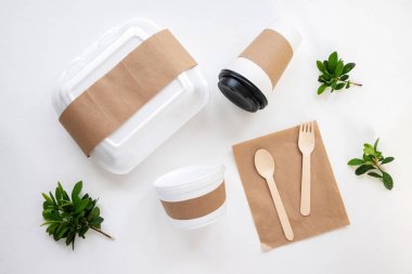 Öğle yemeği şeyleriyle dolu masa. Beslenme çantası, bir fincan, sofra takımı ve yeşillik. Üst görünüm